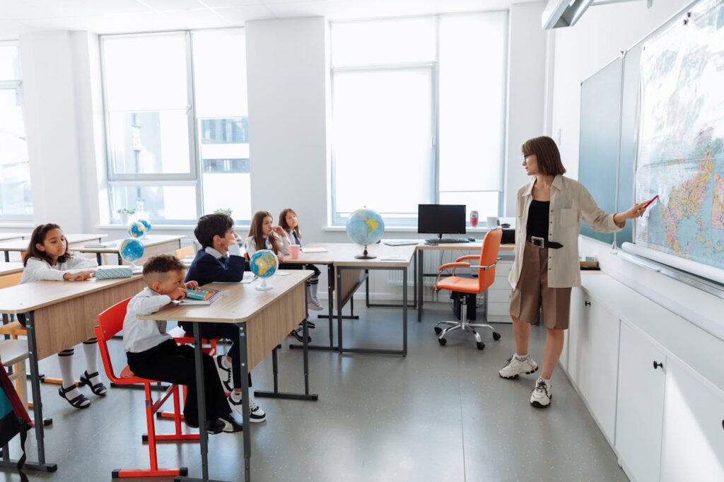 Children in a classroom learning about geography with a teacher using a map.